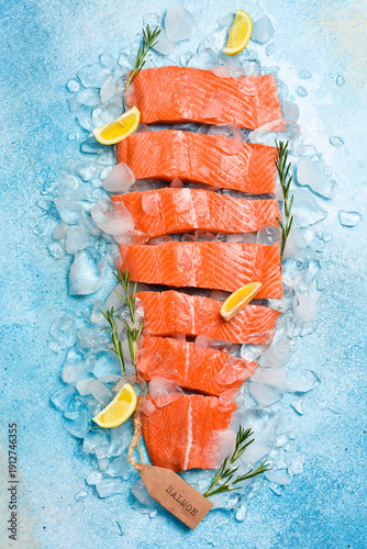 Fresh salmon fillet. Pieces of raw salmon fillet on ice. On a blue stone background. Top view.