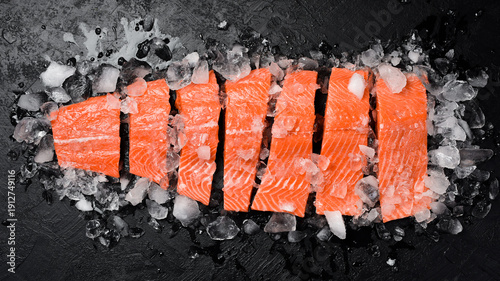 Fresh raw salmon fillet on ice. Fish steak on black stone background. Top view.