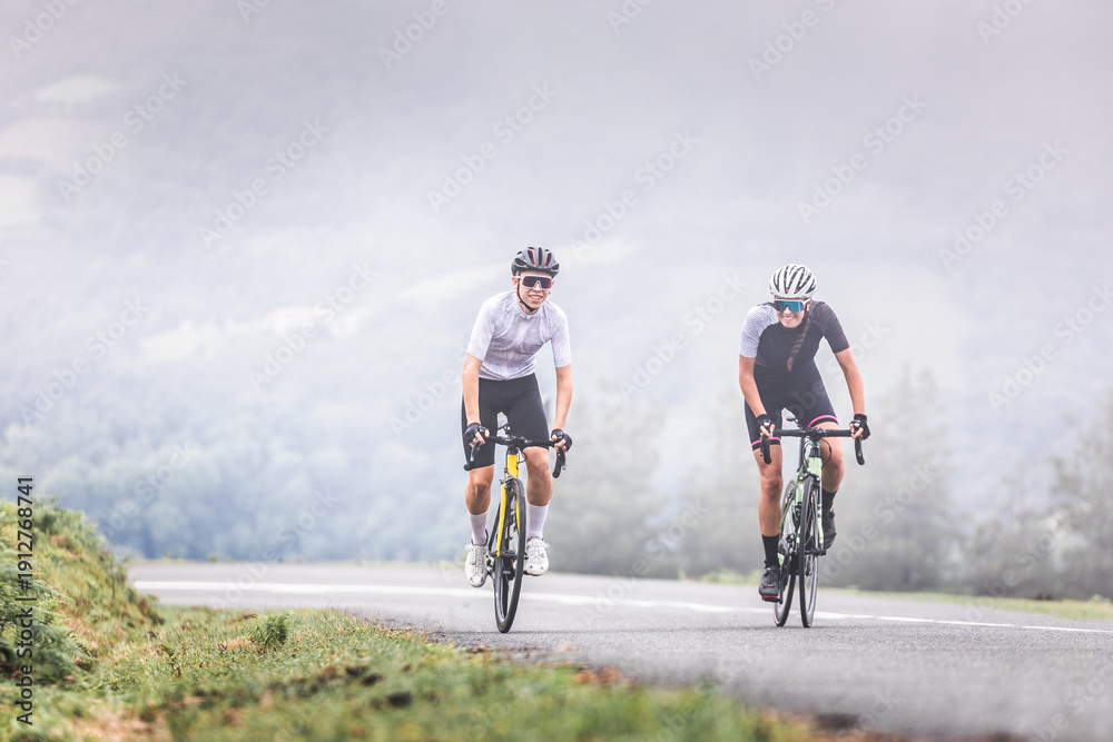 Fototapeta premium Cyclists man and woman couple riding together climbing a mountain at the Aiako Harriak natural park in the Basque Country.