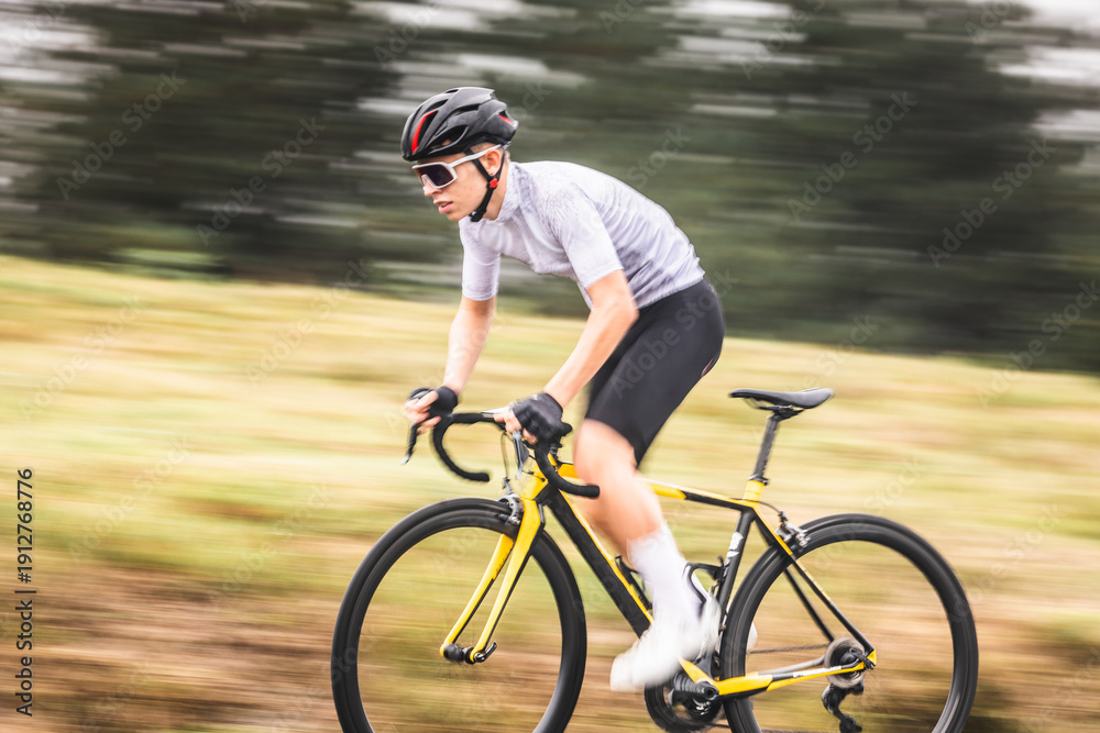 Obraz premium Young caucasian man riding a bike climbing a hill