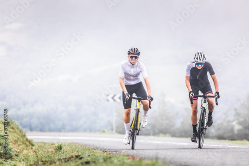 Cyclists man and woman couple riding together climbing a mountain at the Aiako Harriak natural park in the Basque Country.