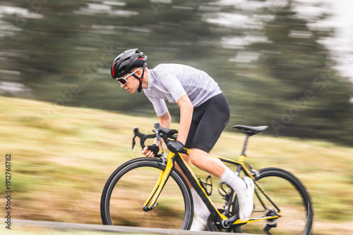 Young caucasian man riding a bike climbing a hill