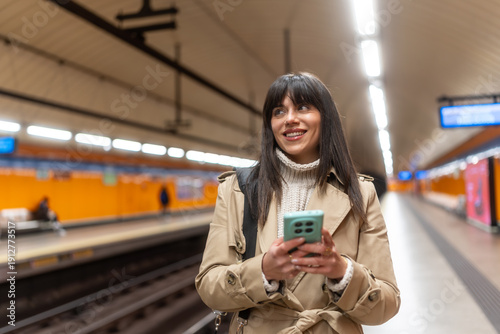Bilde på lerret Young woman commuting, smiling while waiting at subway station platform