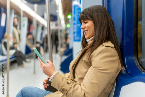 Photos Woman smiling while commuting on subway and using smartphone