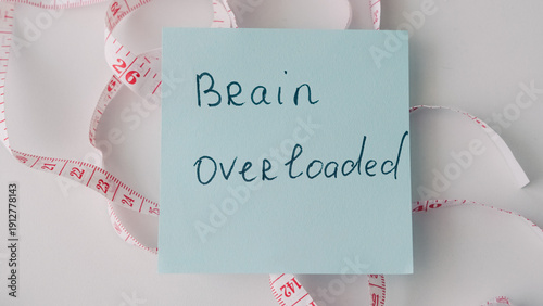 Konstfotografi Sticky note with handwritten text on brain overload surrounded by measuring tape