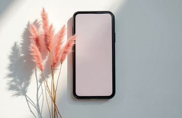 Smartphone with pink dried plants on white surface. Digital device screen blank, suggesting quiet time, rest, or focus. No distractions symbol.