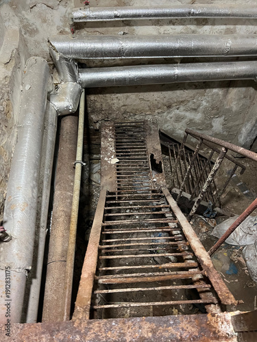 Corroded metal staircase descends into a forgotten underground space