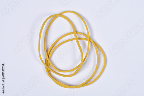 A few thin yellow rubber bands scattered on a plain white background