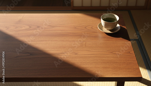 Top view of a traditional Japanese wooden table with a tea cup placed in one corner, leaving large empty space for text. Warm natural light creates a cozy mood.