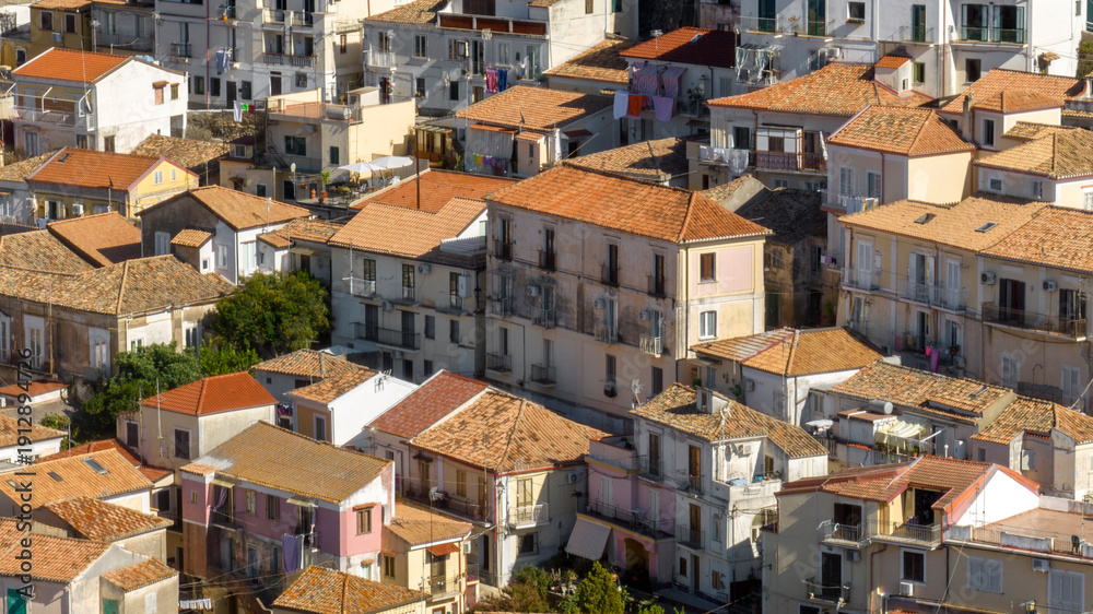 Obraz premium Aerial view of a traditional Italian village, showing a mix of historic buildings with terracotta-tiled roofs. The shot highlights the dense urban layout, with glimpses of balconies and narrow spaces.