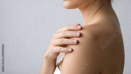 High-quality close-up of a woman touching her smooth shoulder skin. Ideal for skincare, beauty products, and dermatological health branding.