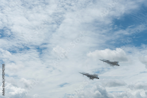 Two fighter jets fly through the sky on technology background