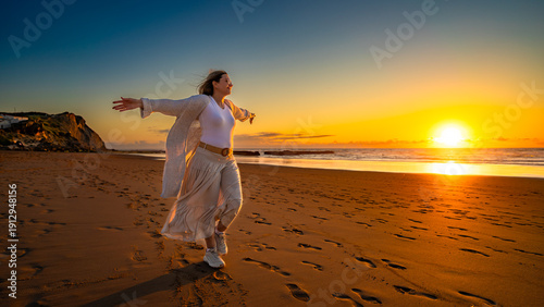 Beautiful middle-aged woman enjoying walk on sandy beach on sunset on windy spring day. Side view