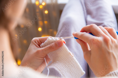 Tableau sur toile A close-up of a young Caucasian woman's hands crocheting a woolen item at home