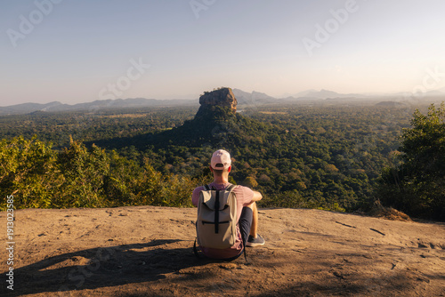 Fotografie Tourist with backpack sittng on Pidurangala Rock and looking at Sigiriya Rock