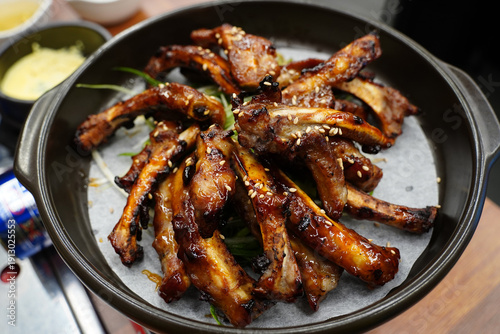 Delicious Korean BBQ grilled pork ribs, Jjokgalbi, with sesame seeds and green onions on a black plate