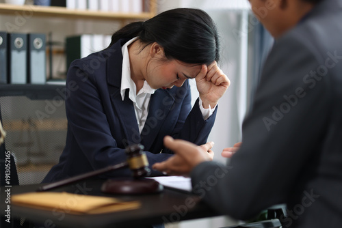 Stressed businesswoman suffering from headache after receiving bad news from her lawyer during legal consultation in office, lawyer is explaining lawsuit details to client.