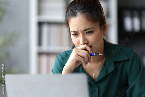 Cuadro en lienzo Stressed businesswoman looking worriedly at laptop screen while working in office, feeling tired and bored with burnout from overwork
