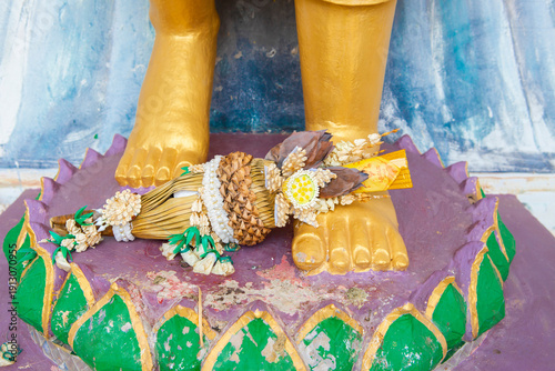 Drying lotus and flowers with incense on the feet of Lord Buddha with selective focus.
