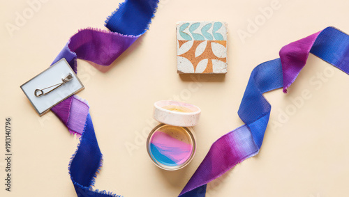 Overhead Composition of Ribbon, Tile, and Paint Jars on a Beige Surface Showcasing Craft Supplies in a Colorful and Organized Arrangement