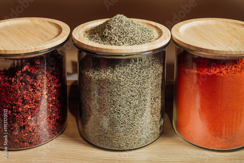 thyme and thyme in bottle on wood background . The seasoning lies on a wooden lid.