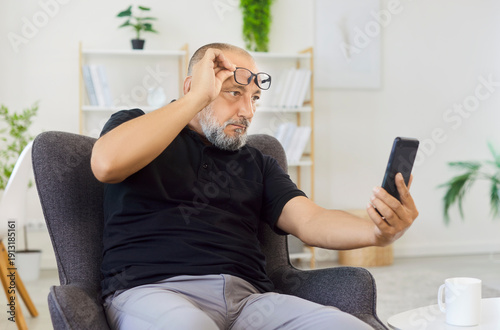 Photos Senior man checking smartphone trying to read message having farsightedness eye disease