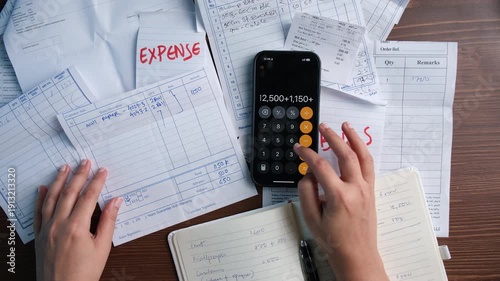 A professional accountant woman at an office desk uses a pen and calculator to manage financial data, tax reports, and budget paperwork for business banking