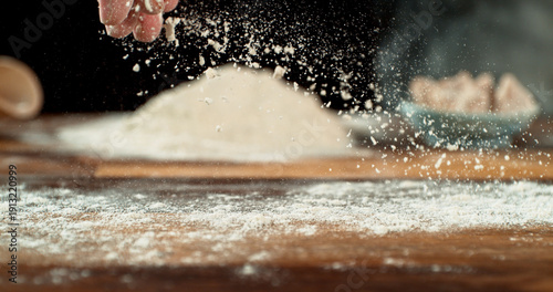 Принти на полотні Close up of baker’s hand tossing flour over prepared risen dough on wooden table