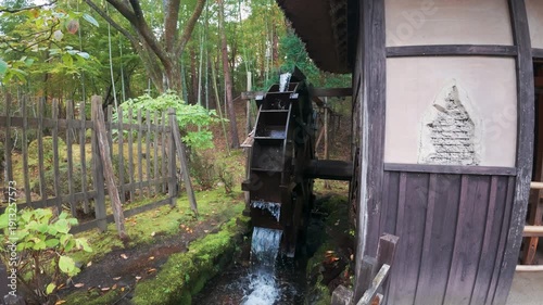 Traditional wooden water wheel turning in a lush green Japanese garden in Nikko