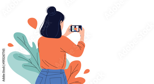 Back view of a young woman with her hair in a bun taking a photo of large green leaves using her smartphone camera.