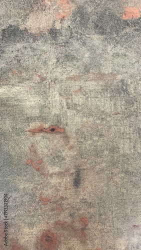 Abstract grunge concrete wall texture with faded reddish stains and weathered surface. Rough urban background with distressed pattern and natural imperfections. Neutral toned backdrop suitable for des