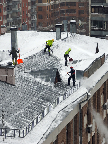 Employees of the municipal service remove snow from the roof of the building, after a heavy snowfall. 