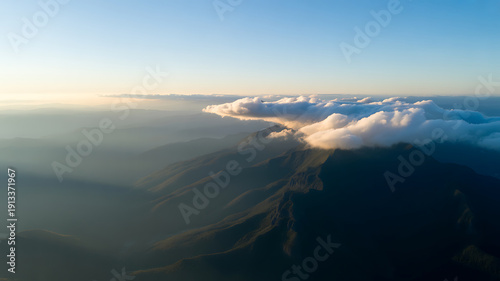Aerial view of mountain peaks above thick white clouds under a clear blue sky landscape