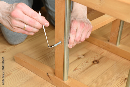 Obraz na płótnie close up of a man using an allen key to build a chair