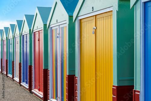 Fotografie Row of colorful wooden beach huts on a sunny day in Hove, England