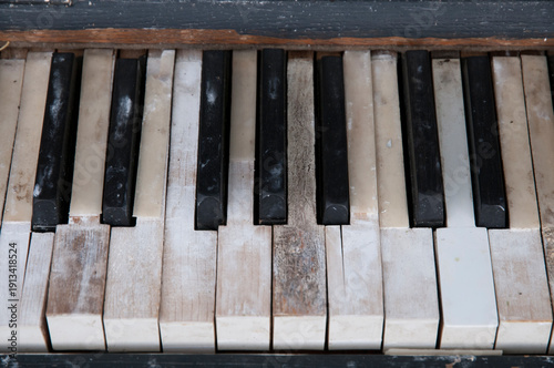 Old weathered piano keys on an instrument that has been left out in the rain.