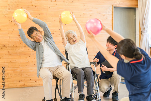 Photos Senior man doing ball exercises at a nursing facility and male and female staff