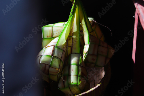 Ketupat or rice dumpling is traditional Muslim food during the celebration of Eid al-Fitr. Ketupat  in bamboo bracket with low light.