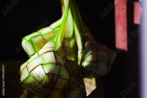 Ketupat or rice dumpling is traditional Muslim food during the celebration of Eid al-Fitr. Ketupat  in bamboo bracket with low light.