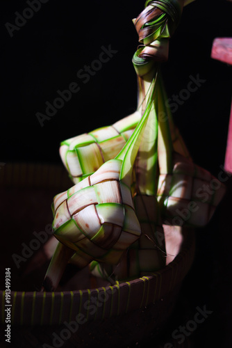 Ketupat or rice dumpling is traditional Muslim food during the celebration of Eid al-Fitr. Ketupat  in bamboo bracket with low light.