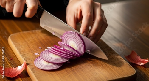 Person slicing fresh onion with kitchen knife on wooden table, close up.
