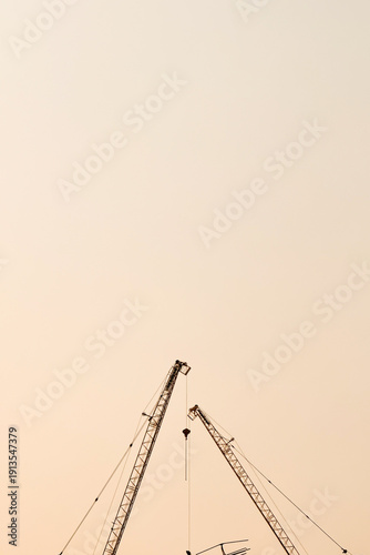 A tall construction crane and an orange sky background.
