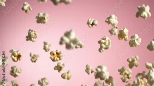 A video showcasing a close up of freshly popped popcorn against a vibrant pink background