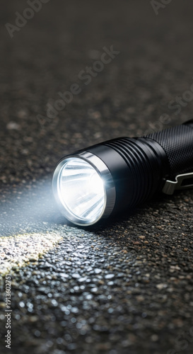 Powerful Tactical LED Flashlight Illuminating Wet Asphalt in the Dark
