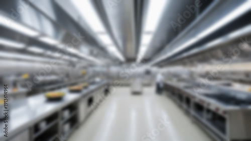 Blurred background of Modern institutional cooking hall with aligned stainless prep islands creating strong leading lines, industrial ceiling with visible piping and LED strips, noon, bright evenly.