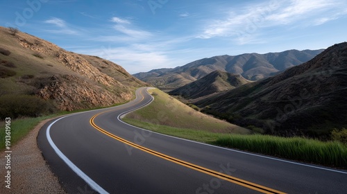 Scenic winding road through green hills and mountains under a clear blue sky with gentle clouds, ideal for travel and nature photography