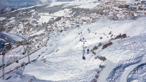 Aerial 4K video from a drone to Sierra Nevada ski resort on a sunny winter day in the mountains, Spain. Sierra Nevada is the largest mountain range near the city of Granada in Spain with snow. Sierra 