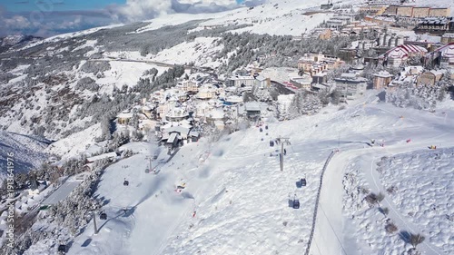 Aerial 4K video from a drone to Sierra Nevada ski resort on a sunny winter day in the mountains, Spain. Sierra Nevada is the largest mountain range near the city of Granada in Spain with snow. Sierra 