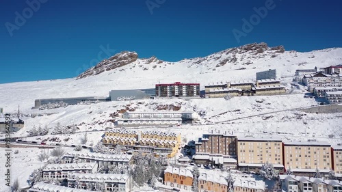 Aerial 4K video from a drone to Sierra Nevada ski resort on a sunny winter day in the mountains, Spain. Sierra Nevada is the largest mountain range near the city of Granada in Spain with snow. Sierra 