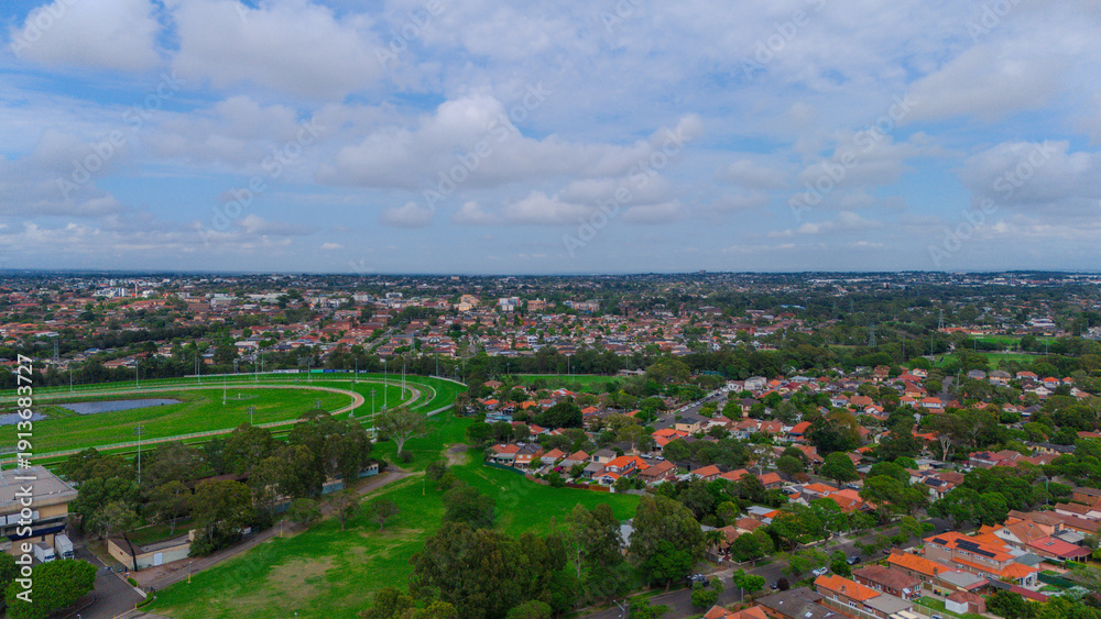 Obraz premium Panoramic Aerial Drone view of Inner Western Suburbs of Sydney housing, roof tops, the streets and the parks, the roads and trees of Ashbury Ashfield Burwood Summer Hill Canterbury and Campsie in Sydn